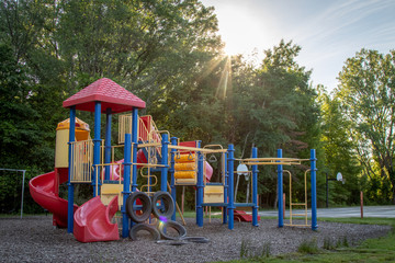  red, blue and yellow playground with sun flare through the trees