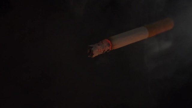 Burning and Smoking cigarette on black background.
