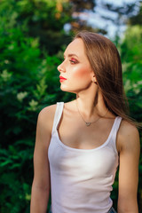 Young woman dressed in white shirt in summer park