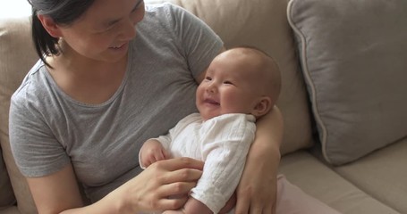 Asian mother holding her 3 months old baby girl in arm and talking to baby at home Chinese baby learning to talk child development concept footage