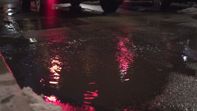 Car drives by puddle with reflection of lights at night 4k