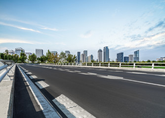 empty asphalt road on modern bridge with city skyline background.
