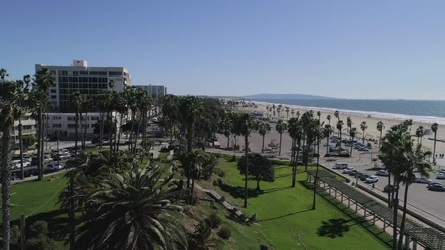 An aerial reveal of Santa Monica Beach, shorelines in Sunny California with a Rise and Rotate movement -  4K 24P