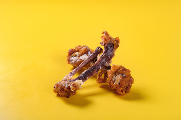 side view bones of deep fried chicken drumstick and wing on yellow background