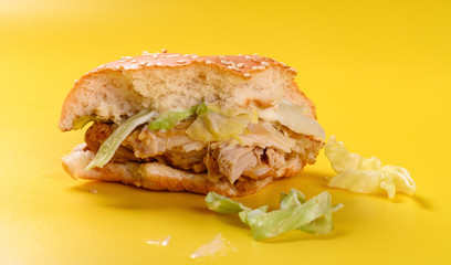 side view half eaten hamburger on a yellow background