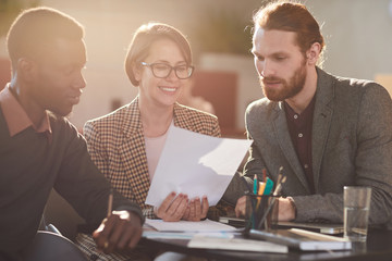 Warm toned portrait of group of business people working in cafe lit by sunlight