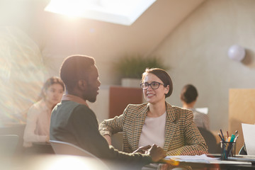 Warm toned portrait of two business people chatting in cafe during coffee break, copy space