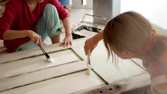 ドアのペンキを塗りなおす女性たち