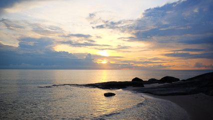 Fototapeta na wymiar Sunrise on cloud sky at tropical sand beach with reef in the morning on rain season.