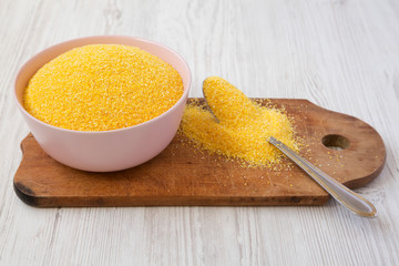 Organic Masarepa corn meal in a pink bowl over white wooden surface, side view. Close-up.