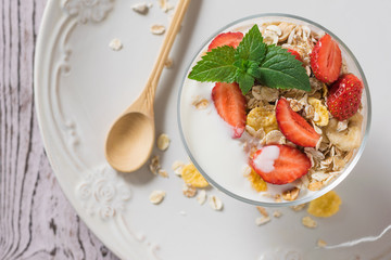 Wooden spoon and bowl of yogurt and berries on the table. Flat lay. The view from the top.