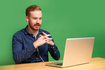 Confident young man in earphones sitting in front of laptop and having video job interview