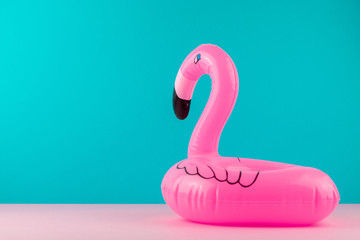 Inflatable pink flamingo on pastel blue and pink background. Pool float party, trendy summer concept. Flat lay, copy space.