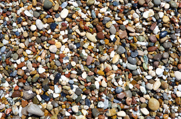 Multi-colored large sea pebbles of various shapes on the sandy shore of the Mediterranean sea for background