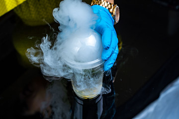 Cocktail with ice vapor on bar desk, close-up. dry ice.