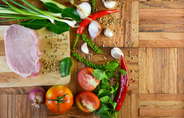 One piece of fresh pork and spices placed on a cutting board and wooden floor