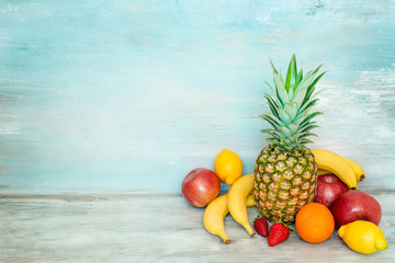 A pile of fresh fruits in front of a blue rustic wooden background.