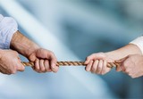 Business people pulling rope in opposite directions at office