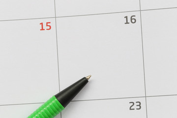 Green pen is placed on the calendar in the 16th day and have copy space.
