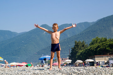 portrait of a boy of seven years old, standing in full growth, on the beach, against the backdrop...