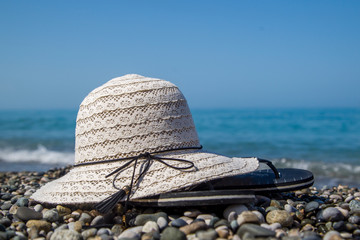 summer accessories for rest, hat and flip flops lie on the seashore