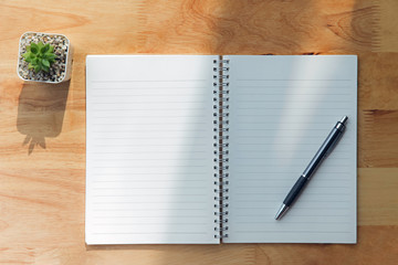 Notebook ,pen ,green plant on wooden background