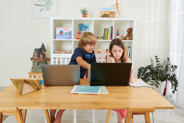 Schoolboy explaining classmate how to white program on laptop