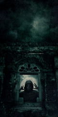 Human skull in jacket standing over ancient castle window, full moon with spooky cloudy sky, Halloween mystery concept
