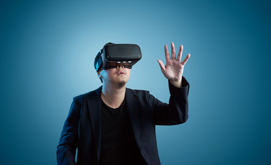 Asian young amazed businessman wearing virtual reality headset isolated on gradient blue background .Future multimedia visual effects technology concept .
