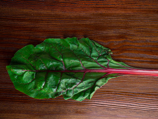 Fresh raw leaves of chard, leaf beets, mangold, swiss chard on a wooden table, close up