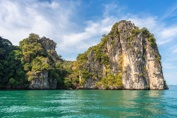 Fototapeta na wymiar Picturesque rock covered with tropical greenery in the water of the azure Andaman sea on Hong island in Thailand under the blue sky