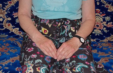 Woman in multicolored dress sitting on the multicolored sofa