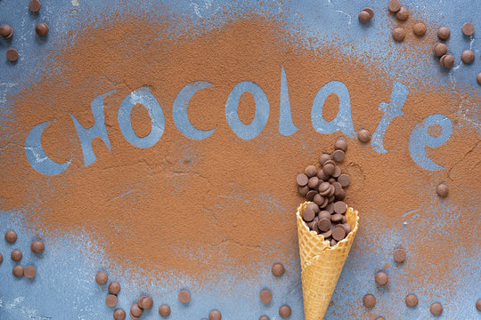 Chocolate drops in a waffle cone and word Chocolate made by cocoa pouder