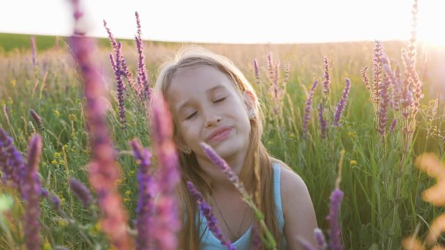 Little girl in flowers field. The child hides behind the flowers in the field.