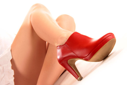 Roter Schuh mit Stöckelabsatz am nackten Bein einer Frau