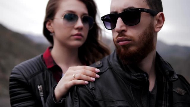 lady hand with golden ring hugs handsome man in black leather jacket and sunglasses extreme close view
