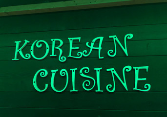 Korean cuisine neon sign on a wooden wall at night