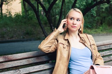 Blonde woman in casual clothes tolking on the phone with a serious face.