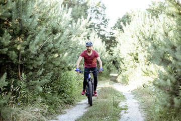 Cyclist riding mountain bicycle on the forest road during the summer time