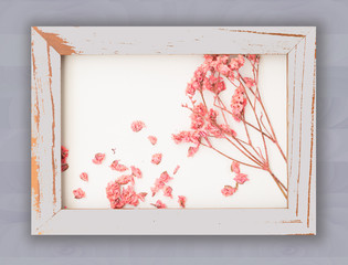 Beautiful pink dried flowers decorated with vintage wooden frame  on rose wallpaper background,top view