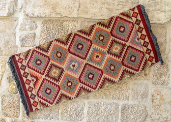 Bright Turkish carpets hanging on a stone wall