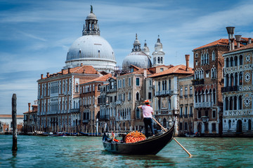 Traditional Gondola and gondolier on Canal Grande with Basilica di Santa Maria della Salute in the background in Venice, Italy. Summer vacation city trip