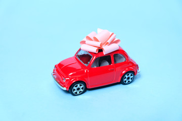 The red car is tied with a gift bow. The concept of a present.