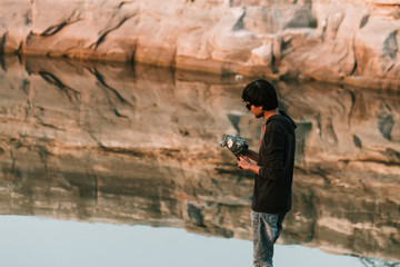 Indian model wearing sunglasses posing in front of the cliff besides lake