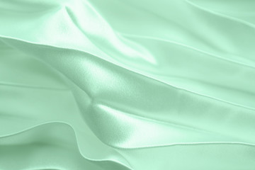 Neo mint color soft satin folded fabric background texture. Close up of ripples on silk fabric. Neo mint color 2020 year concept. Soft cloth background