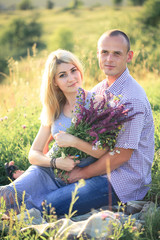 Man and woman on nature with a bouquet of flowers. Couple in love.