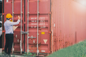 Male engineer inspection checking on container background With note on notepad or...
