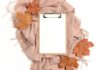 Composition with clipboard mockup, dry maple leaves, brown scarf on white background