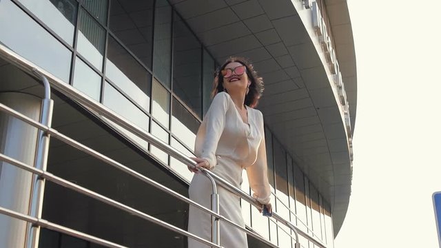 Woman walking and talking on cellphone in the city near scyscraper building in slow motion.