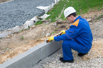 road construction worker measures road slope level